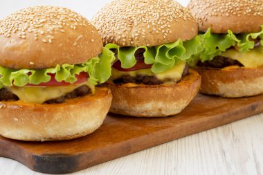 Rustik ahşap tahta üzerinde ev yapımı çizburger, yan görünüm. Closeu