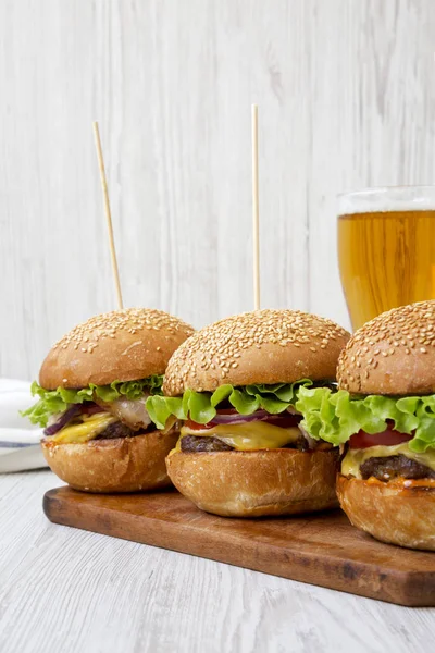 Domácí cheeseburgery a sklenice piva na bílém dřevěném surfa — Stock fotografie