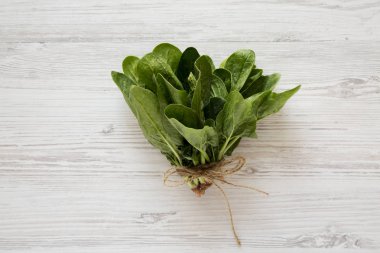 Beyaz ahşap yüzeyde taze çiğ ıspanak, üst görünümü. Düz yatıyordu,