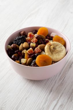 Beyaz ahşap backgroun üzerinde pembe bir kapta kurutulmuş meyve ve fındık