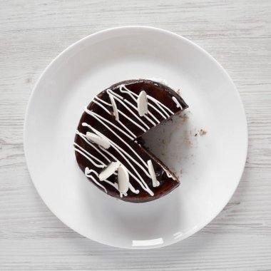 Beyaz odun üzerinde beyaz bir tabak üzerinde ev yapımı çikolatalı kiraz kek