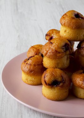 Beyaz ahşap s üzerinde pembe bir tabak üzerinde kiraz ile ev yapımı kekler