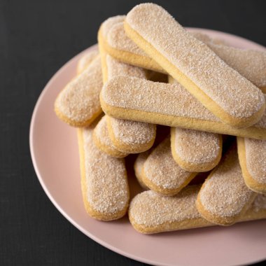 Siyah sırt üzerinde pembe bir tabak üzerinde Savoiardi veya ladyfingers çerezleri