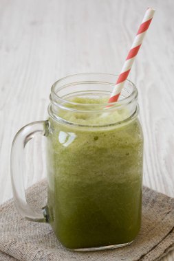 Beyaz ahşap backgroun üzerinde cam bir kavanozda yeşil kereviz smoothie