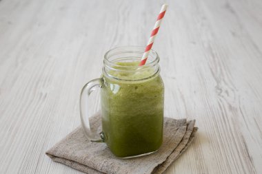 Beyaz ahşap backgroun üzerinde cam bir kavanozda yeşil kereviz smoothie