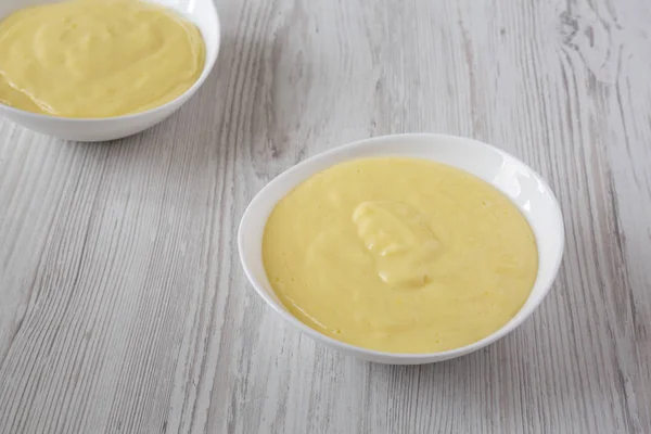 Hemlagad vanilj vaniljsås pudding i skålar över vita trä tillbaka — Stockfoto