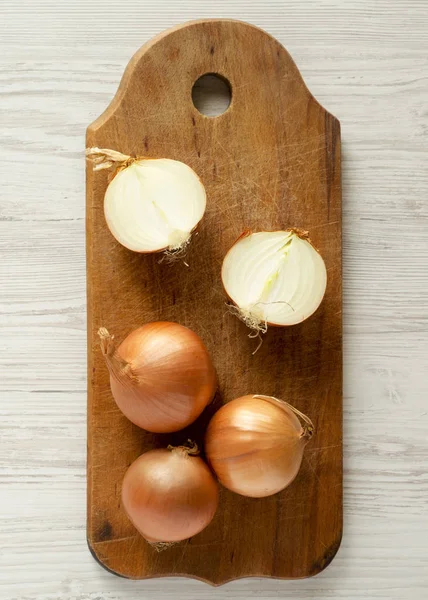 Unpeeled raw organic yellow onions on rustic wooden board over w — Stock Photo, Image