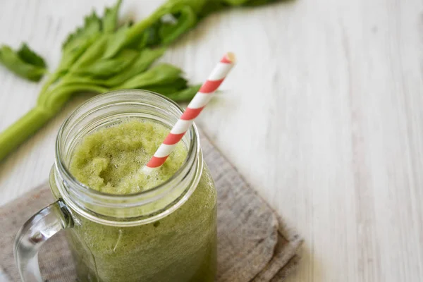 Green celery smoothie in a glass jar over white wooden surface, — Stock Photo, Image