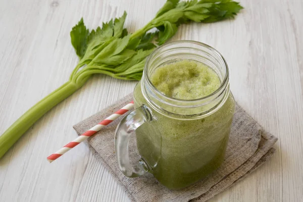 Green celery smoothie in a glass jar over white wooden backgroun — Stock Photo, Image