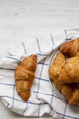Beyaz ahşap yüzeyde taze kruvasan, üst görünümü. Yukarıdan