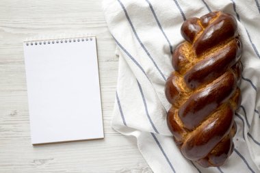 Beyaz bir ağaç üzerinde ev yapımı challah yahudi ekmek ve boş not defteri