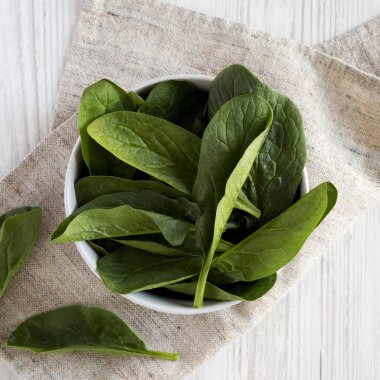 Beyaz ahşap yüzey üzerinde bir kapta ıspanak, üst görünümü. Yükü,