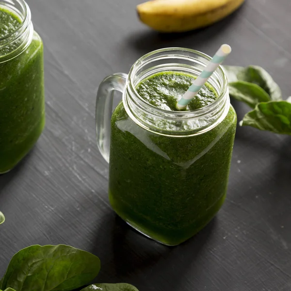 Green smoothie with avocado, spinach and banana in glass jars ov