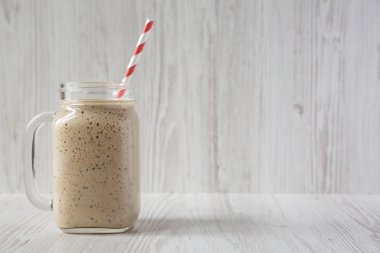 Beyaz üzerinde cam bir kavanozda ev yapımı muz, kivi, elma smoothie 