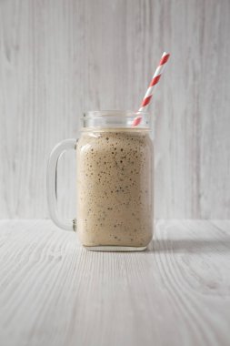 Beyaz üzerinde cam bir kavanozda ev yapımı muz, kivi, elma smoothie 