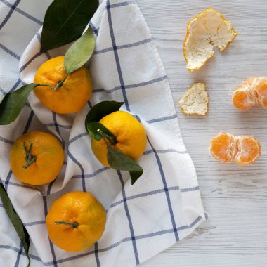 Beyaz ahşap bir masa üzerinde taze olgun mandalina, üst görünümü. Düz la