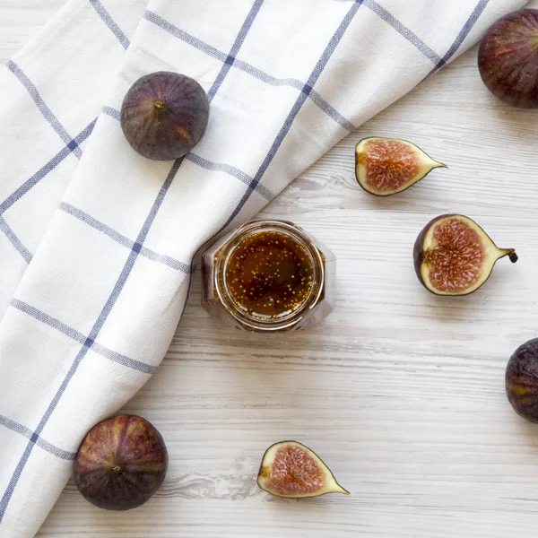 Glass jar of fig jam and fresh figs on a white wooden surface. T — Stock Photo, Image