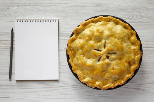 Hjemmelavet æbletærte og blank notesblok med blyant på hvidt træ - Stock-foto