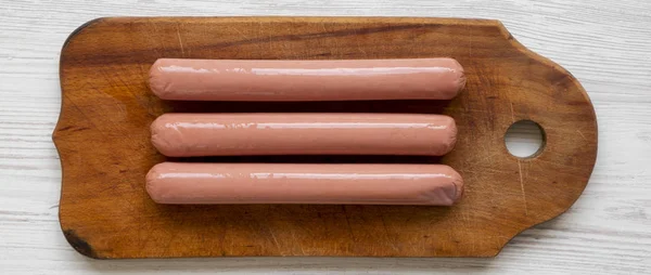 Hot dog sausages on wooden board over white wooden surface, over — Stock Photo, Image
