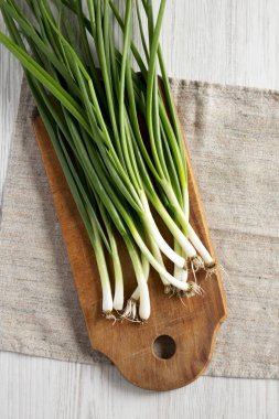 Beyaz ahşap backgrou bir kesme tahtası üzerinde taze yeşil soğan