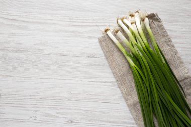 Beyaz ahşap bir yüzey üzerinde taze yeşil soğan, havai görünümü. Fro