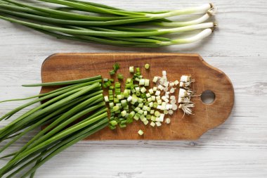 Rustik ahşap bir tahta üzerinde doğranmış yeşil soğan, üst görünümü. Overhea
