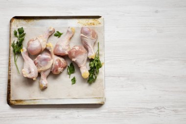 Tepside bir fırın kağıdı üzerinde pişmemiş çiğ tavuk baget 