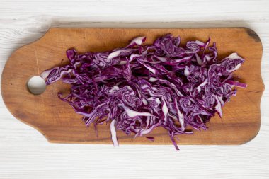 Beyaz ahşap backgro üzerinde bir kesme tahtası üzerinde doğranmış kırmızı lahana