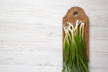 Beyaz ahşap backgrou bir kesme tahtası üzerinde taze yeşil soğan