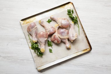 Tepside bir fırın kağıdı üzerinde pişmemiş çiğ tavuk baget 