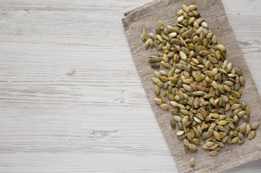 Beyaz ahşap bir masa üzerinde kavrulmuş kabak çekirdeği, üst görünümü. Düz la