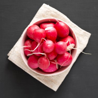 Siyah arka plan üzerinde pembe bir kapta taze kırmızı turp, overhea