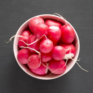 Siyah arka plan üzerinde pembe bir kapta taze kırmızı turp, overhea