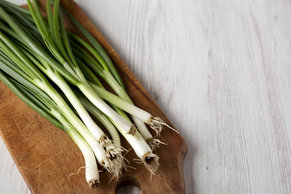 Chopped green onions on a rustic wooden board, side view. Close- — Stock Photo, Image
