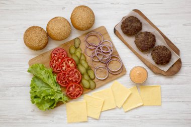 Beyaz ahşap yüzeyüzerinde Cheeseburger malzemeler, üst görünümü. Cl