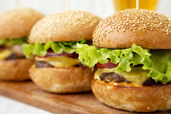 Domácí cheeseburgery na rustikální dřevěné desce a sklo studené — Stock fotografie