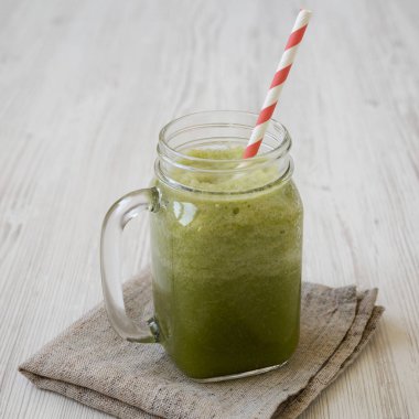 Beyaz ahşap yüzey üzerinde cam bir kavanozda yeşil kereviz smoothie, 