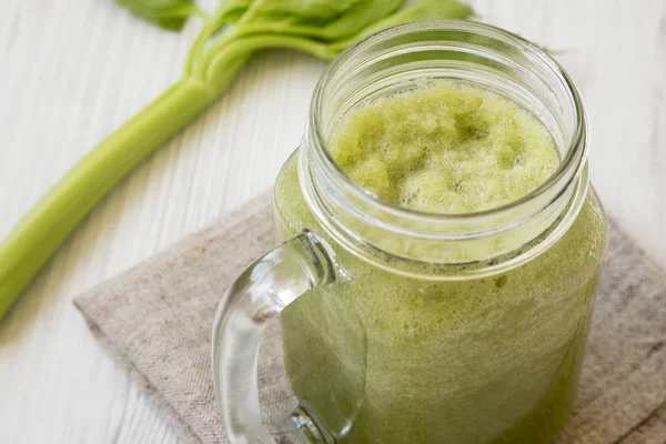 Glass jar mug filled with celery smoothie on a white wooden back — Stock Photo, Image