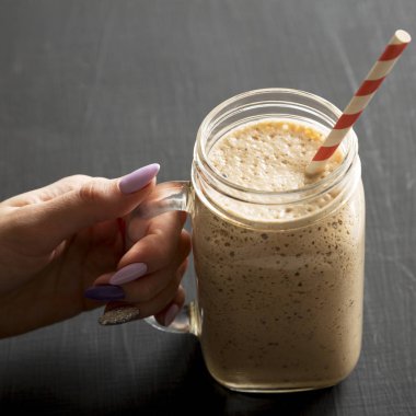 Bir kadının elinde muz dolu cam kavanoz fincanı var.