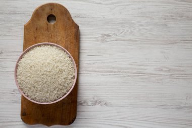 Pembe kase rustik ahşap üzerinde kuru beyaz pirinç basmati ile dolu 