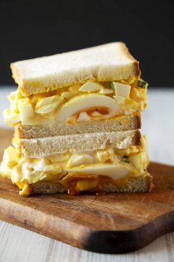 Rustik ahşap tahta üzerinde ev yapımı yumurta salatası sandviç, yan görünüm.