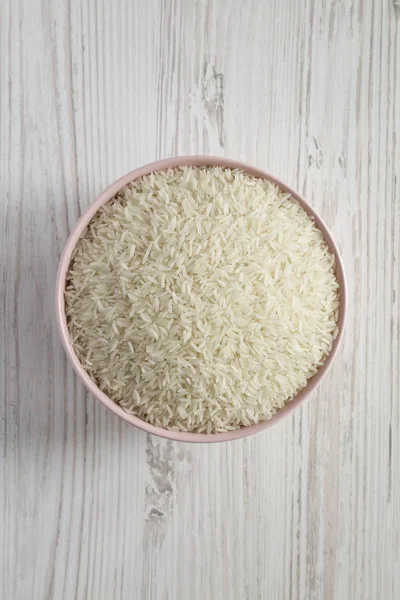 Dry white rice basmati in a pink bowl over white wooden surface, — Stock Photo, Image