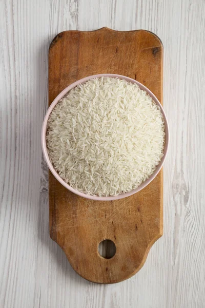 Růžová miska naplněná suchou bílou rýží Basmati na rustikálním dřevěném — Stock fotografie