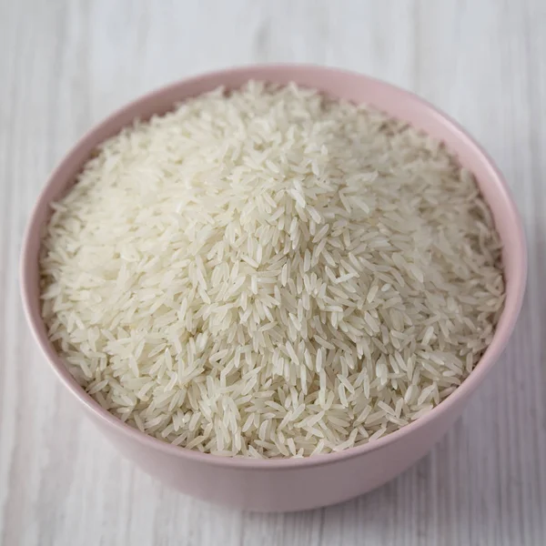 Suchy biały ryż basmati w misce różowy biały powierzchni drewnianych, — Zdjęcie stockowe