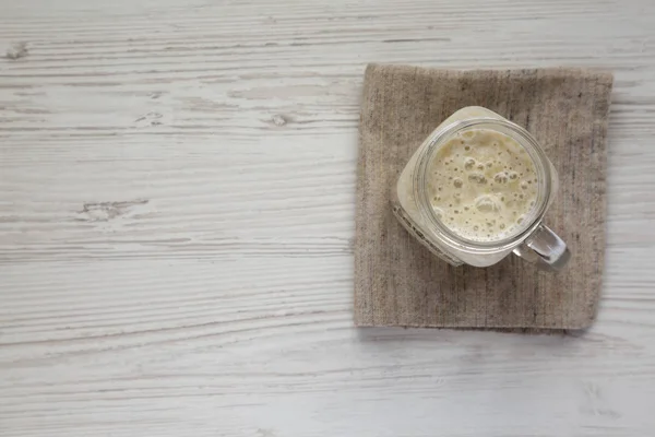 Mangkuk kaca Mason diisi dengan smoothie pisang di atas kayu putih — Stok Foto