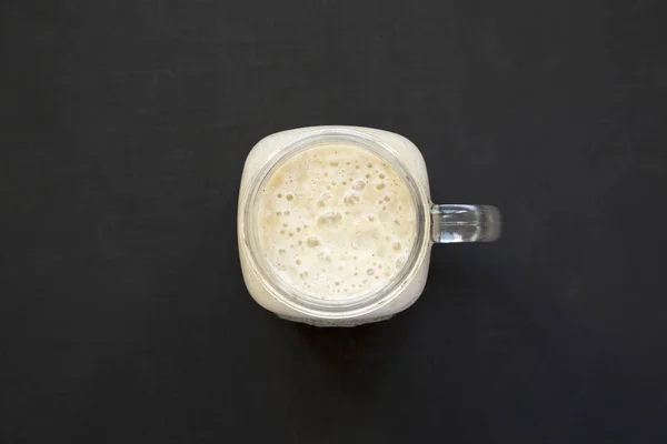 Mangkuk kaca Mason diisi dengan smoothie pisang di atas backg hitam — Stok Foto