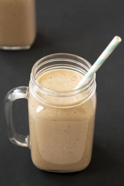 Siyah artalan üzerinde cam kavanozlarda sağlıklı muz elma Smoothie