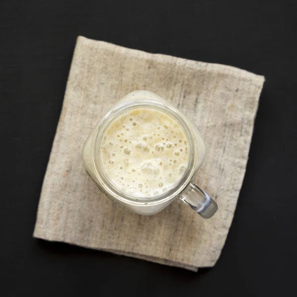 Pisang smoothie dalam gelas jar mug di atas meja hitam, top view. F — Stok Foto