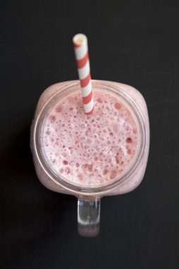 Siyah backgro üzerinde cam bir kavanoz kupa çilek muz smoothie