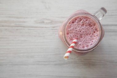 Beyaz ahşap üzerinde cam bir kavanoz kupa çilek muz smoothie 
